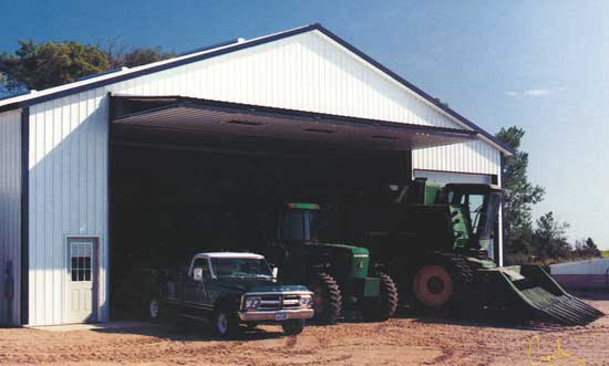 Farm building storing farm equipment with bifold door