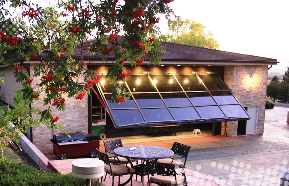 Custom Schweiss glass hydraulic door installed on a garage that opens up to a patio in Denver shown open