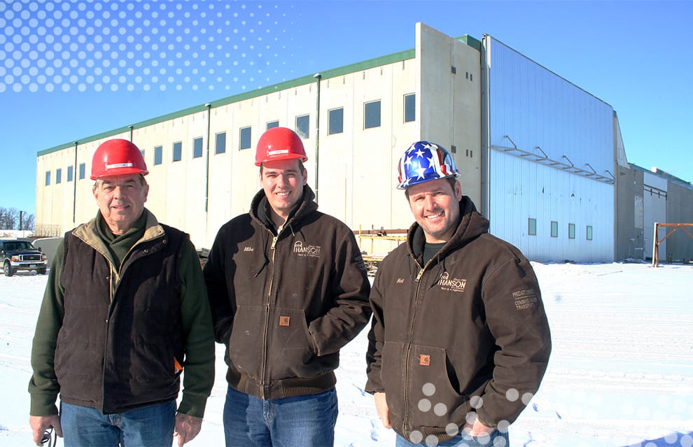 Three gentlemen posing outside Schweiss bifold door fitted at Hanson Silo Company