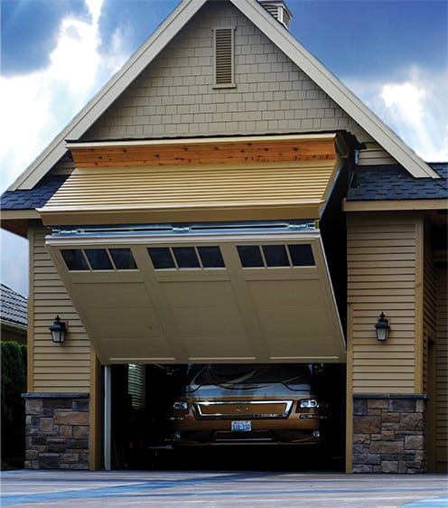 Custom Schweiss bifold door tall enough to store an RV fitted on a garage shown half-open