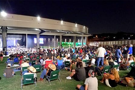 Large crowd sitting outside enjoying concert through opened Schweiss bifold doors fitted on Toyota Music Factory