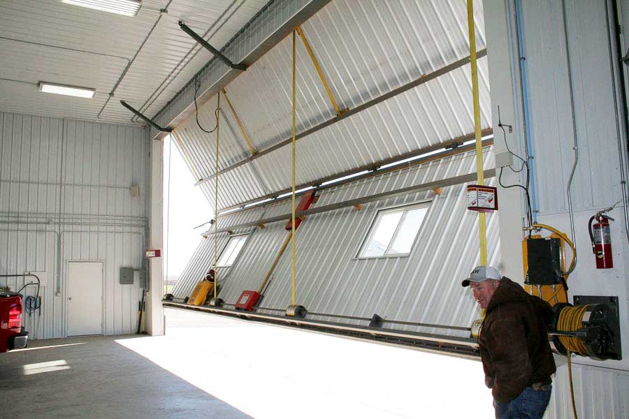 Shed owner showing off how easy to open a Schweiss Door when storing equipment 