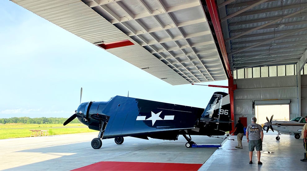 Classic military plane parked underneath opened Schweiss hydraulic door